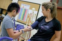 One student examining another with a stethoscope