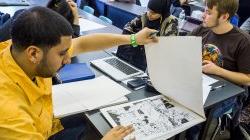 Student flipping through sketch pad revealing inked comic book style pages