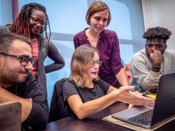 students and faculty gathered around laptop